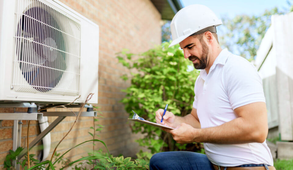 Contractor in Hard Hat With Clipboard and Heat Pump
