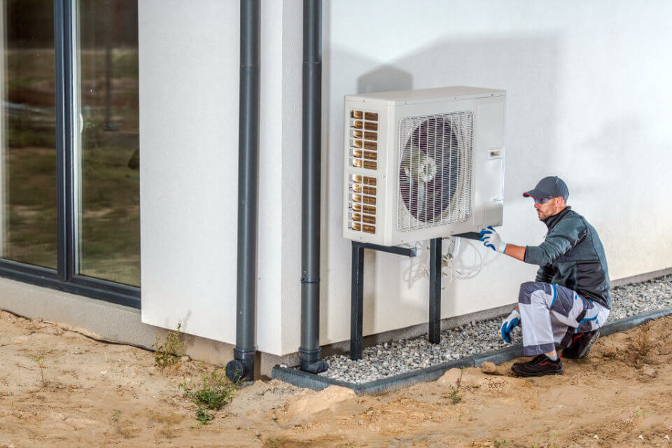 Contractor Crouching at Heat Pump